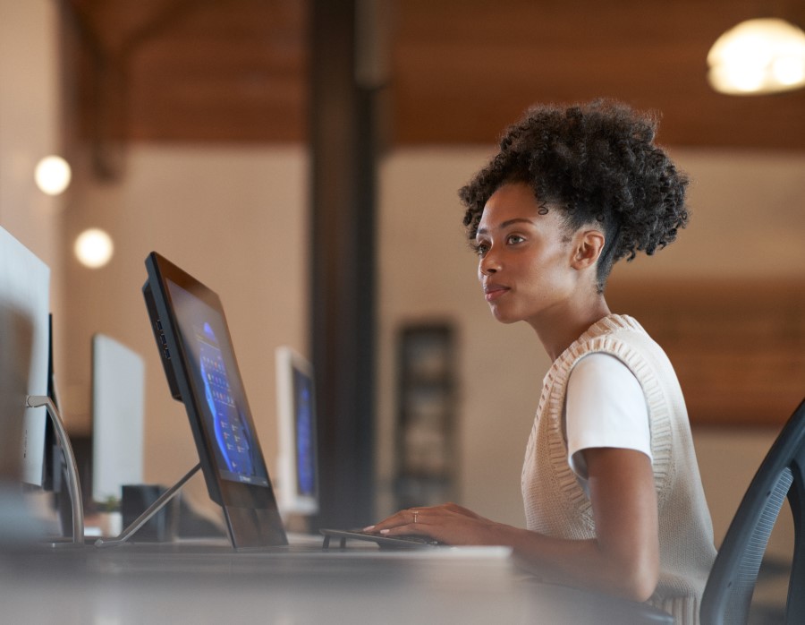 A woman sitting at a desk in front of a computer, looking off to the side.