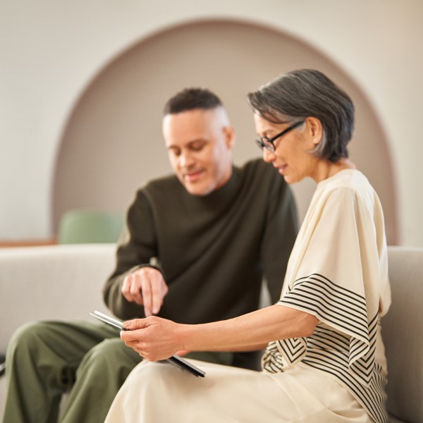 Collaboration between a developer and professions consultant, sitting on a couch looking at a tablet