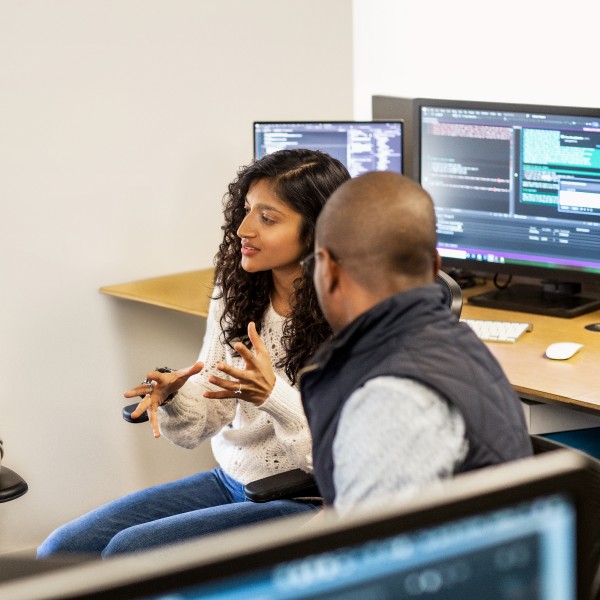 Female developer leads impromptu meeting while working in a shared space.